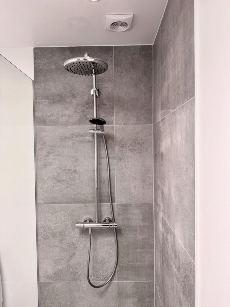 Badeværelse renovering med væghængt toilet og elegant bruseniche