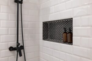 Hvide metrofliser i bruser med niche i sort mosaik og sort armatur